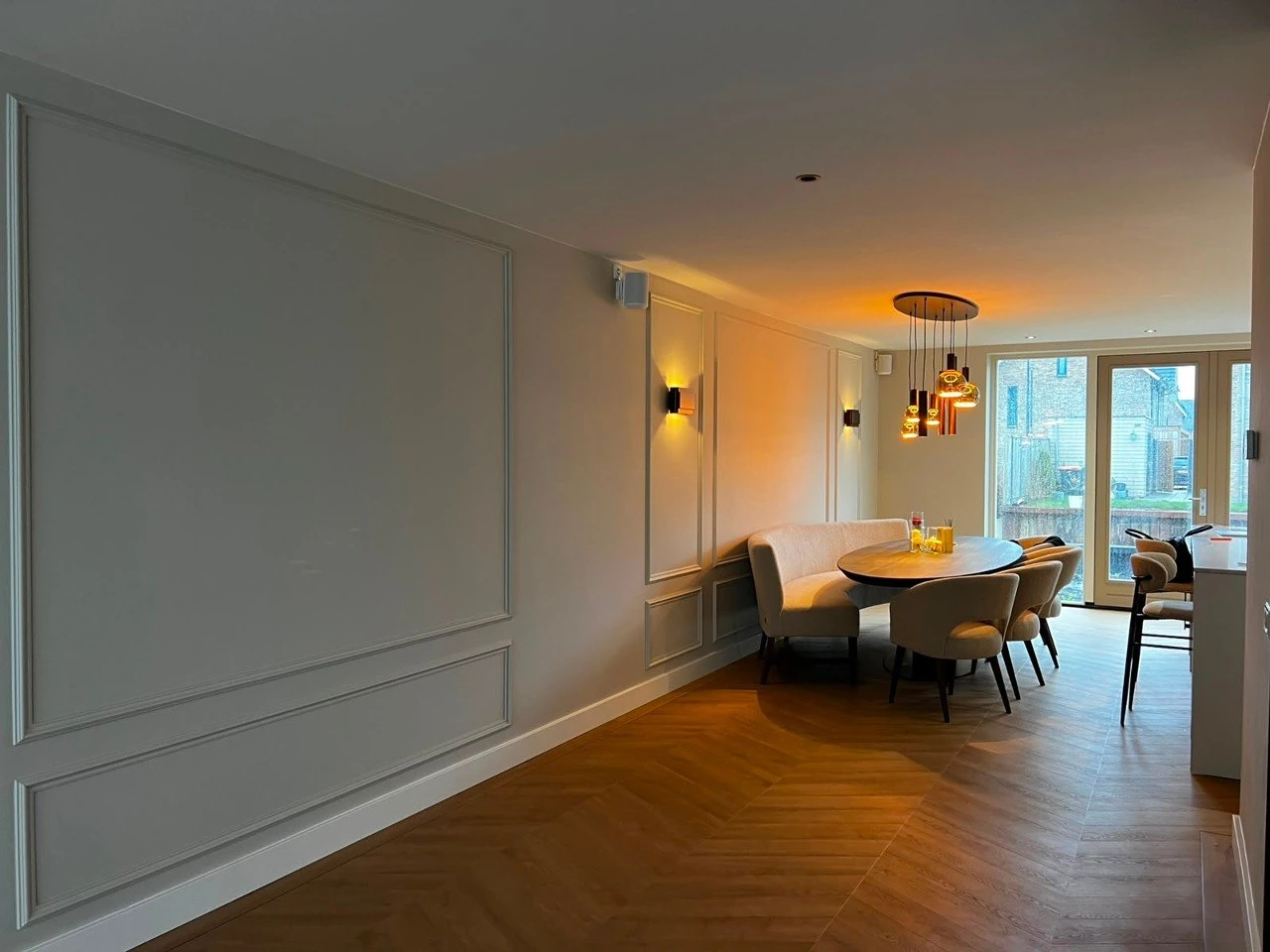 Smalle eetkamer met houten tafel, hanglamp en licht afgewerkte wanden