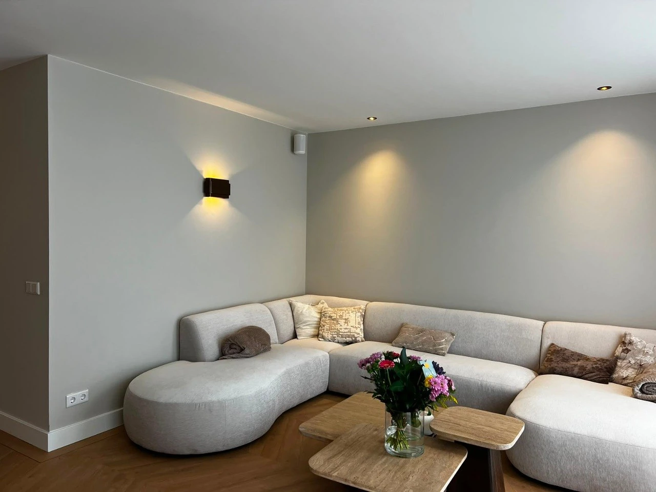 Woonkamer met bank, donkere wand en warm wandlicht